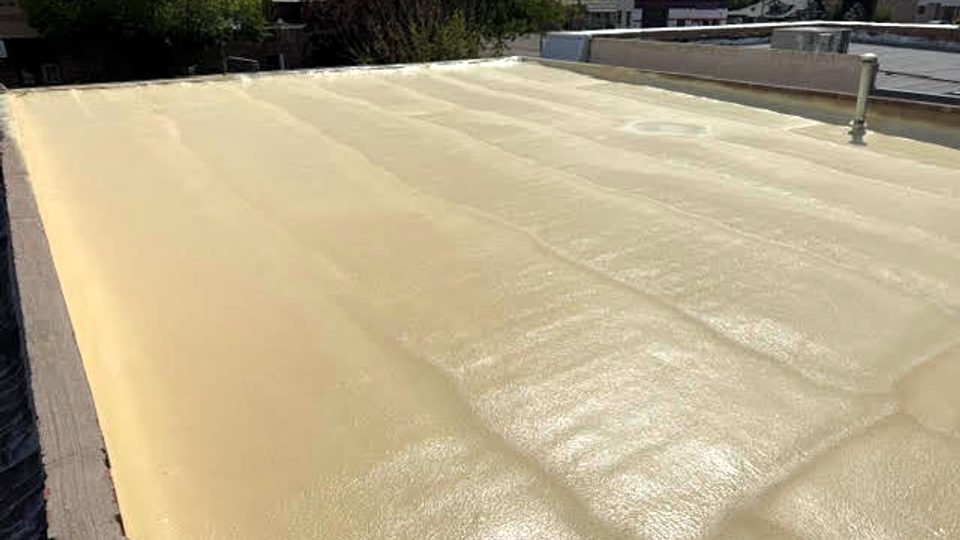 Before: bare tan spray polyurethane foam roof on a commercial building in Pueblo, Colorado, uncoated and exposed to sunlight