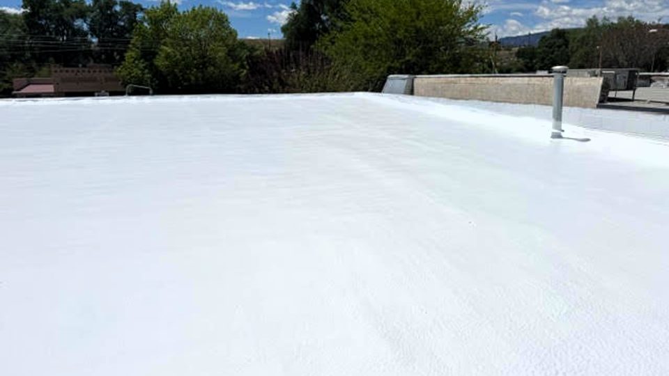 After: the same Pueblo, Colorado spray foam roof finished with a bright white Conklin reflective coating and sealed rooftop vent