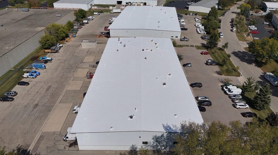After: the same Wisconsin metal warehouse roof coated bright white with a Conklin reflective roof system